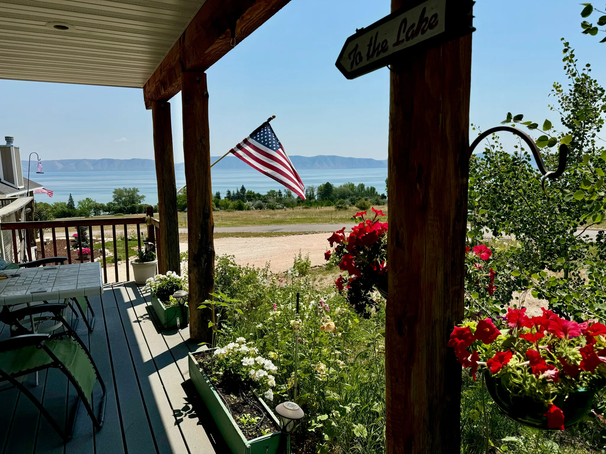 Southentrance, covered deck with wood-finish railings and posts overlooking beautiful Bear Lake, American flag display
