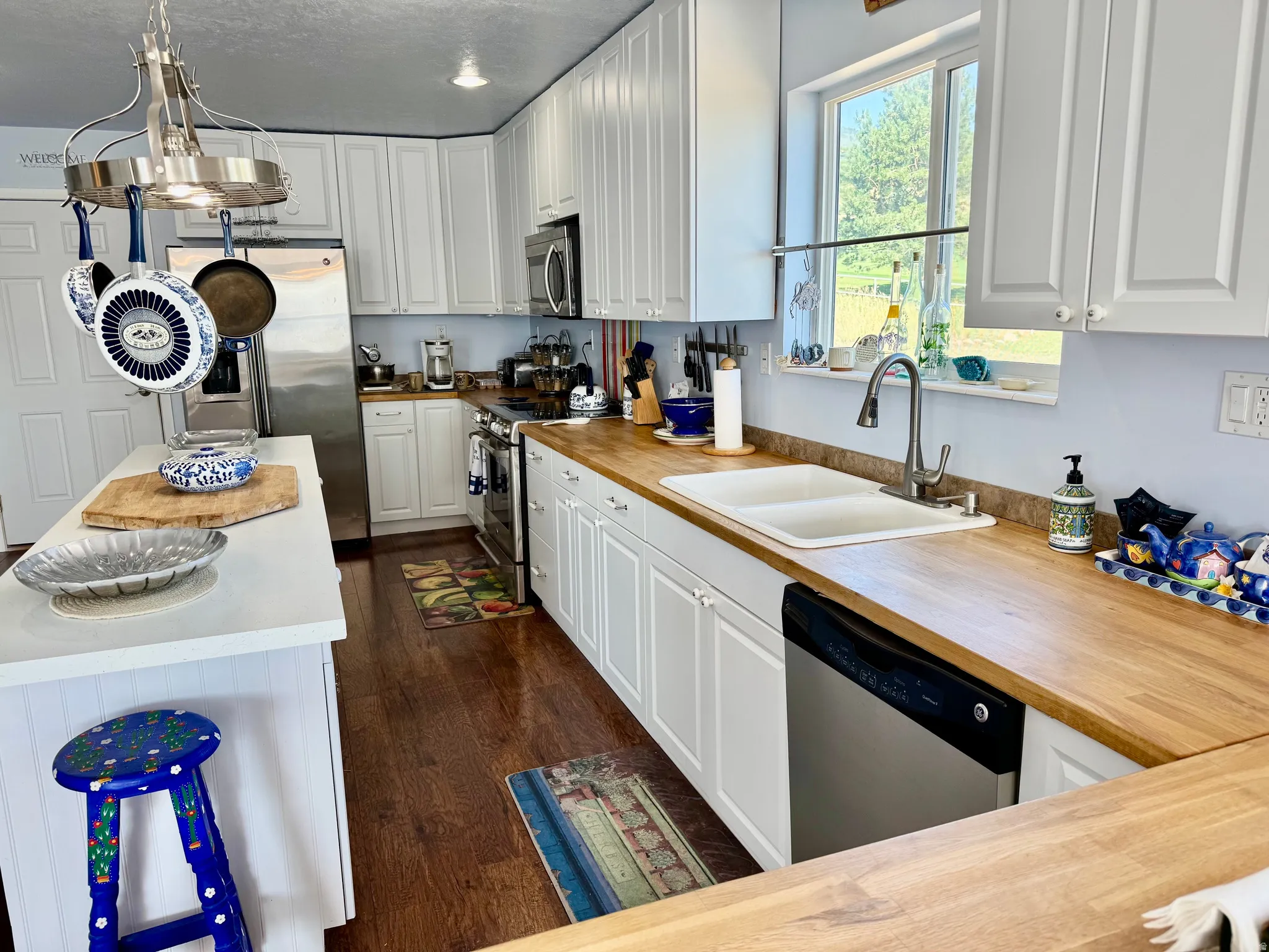 Kitchen featuring white cabinetry, wood-finish countertops, stainless steel appliances, and a dual-basin sink