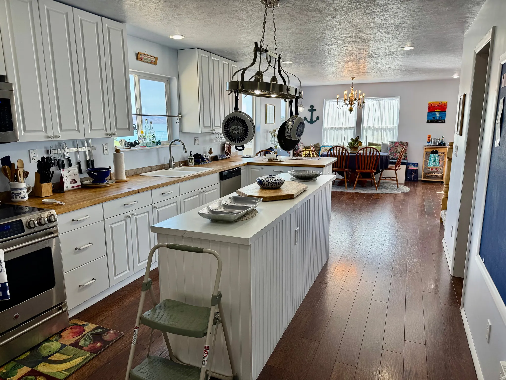 White cabinetry with chrome hardware, wood-finish countertops, and a central island with beadboard detailing
