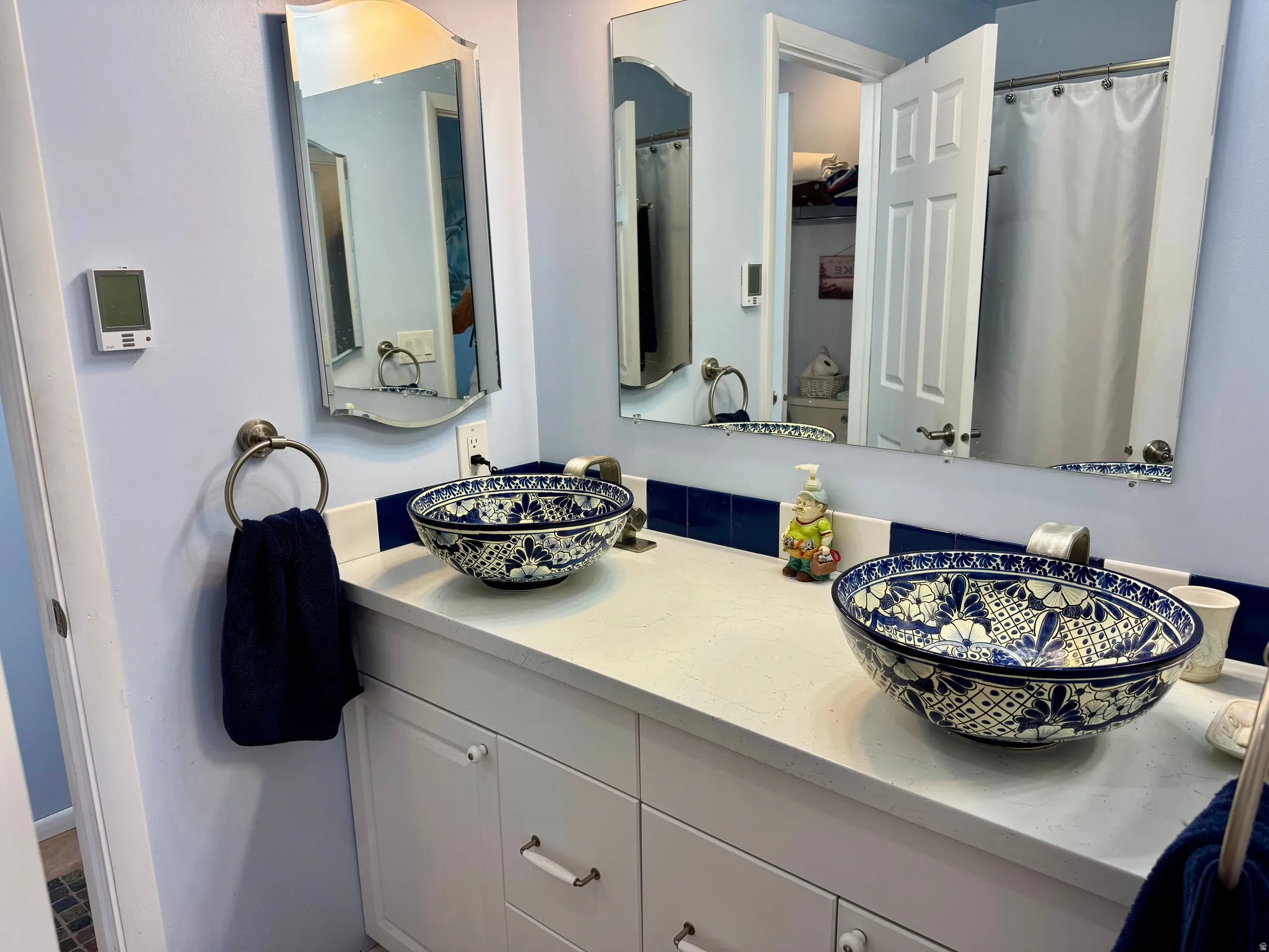 Primary bathroom, with dual vessel sinks with intricate blue and white patterns, white countertop, and white cabinetry