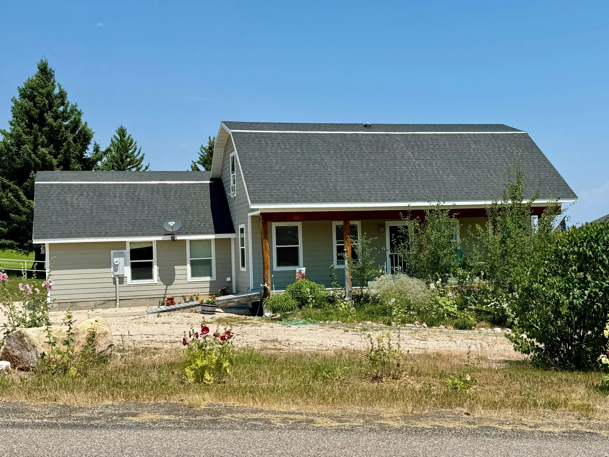 South side of two-story residence featuring a covered front porch, dark shingle roof, and light siding
