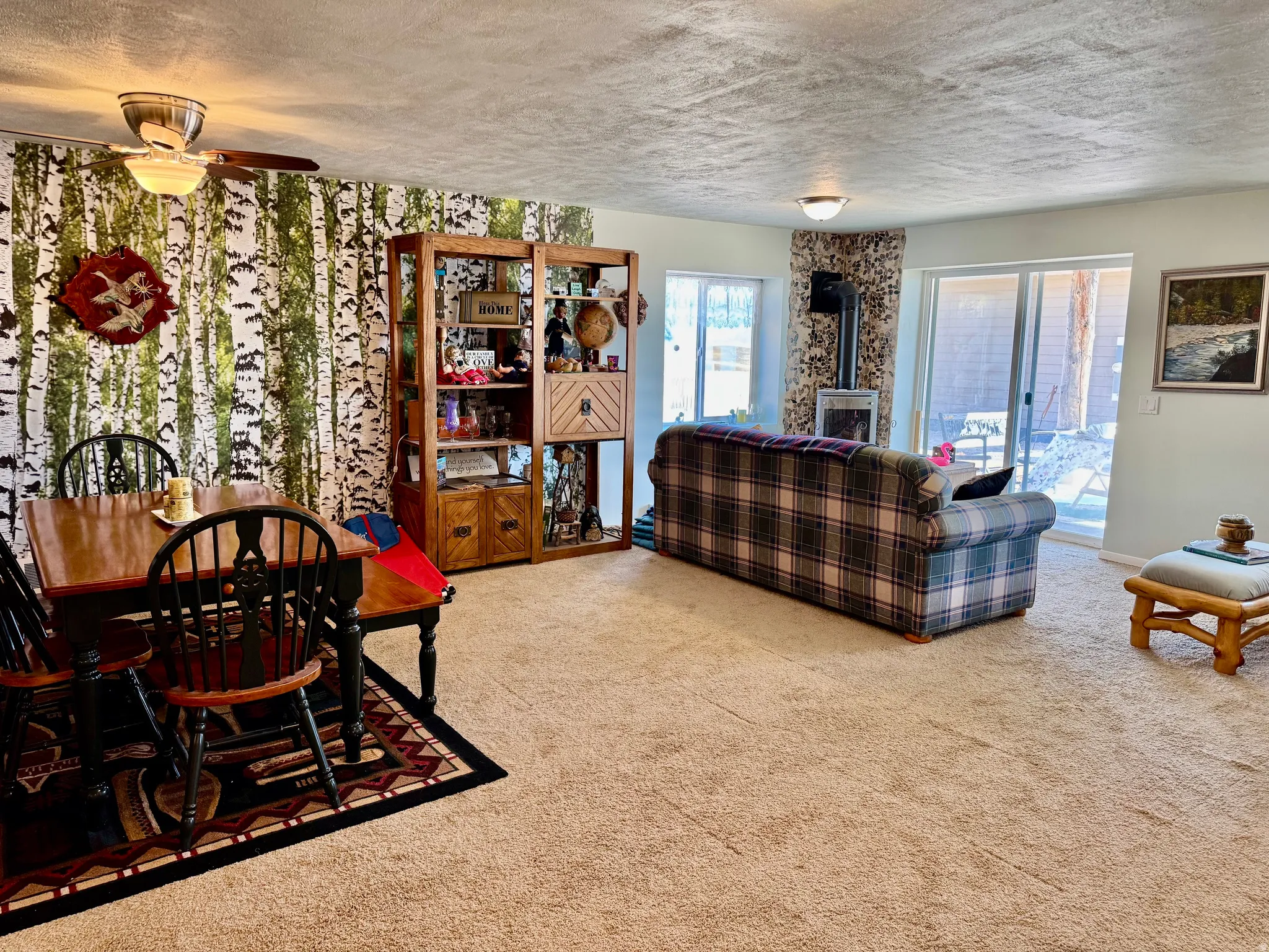 Lower level living area with an accent wall, ceiling fan, and sliding glass door to patio.