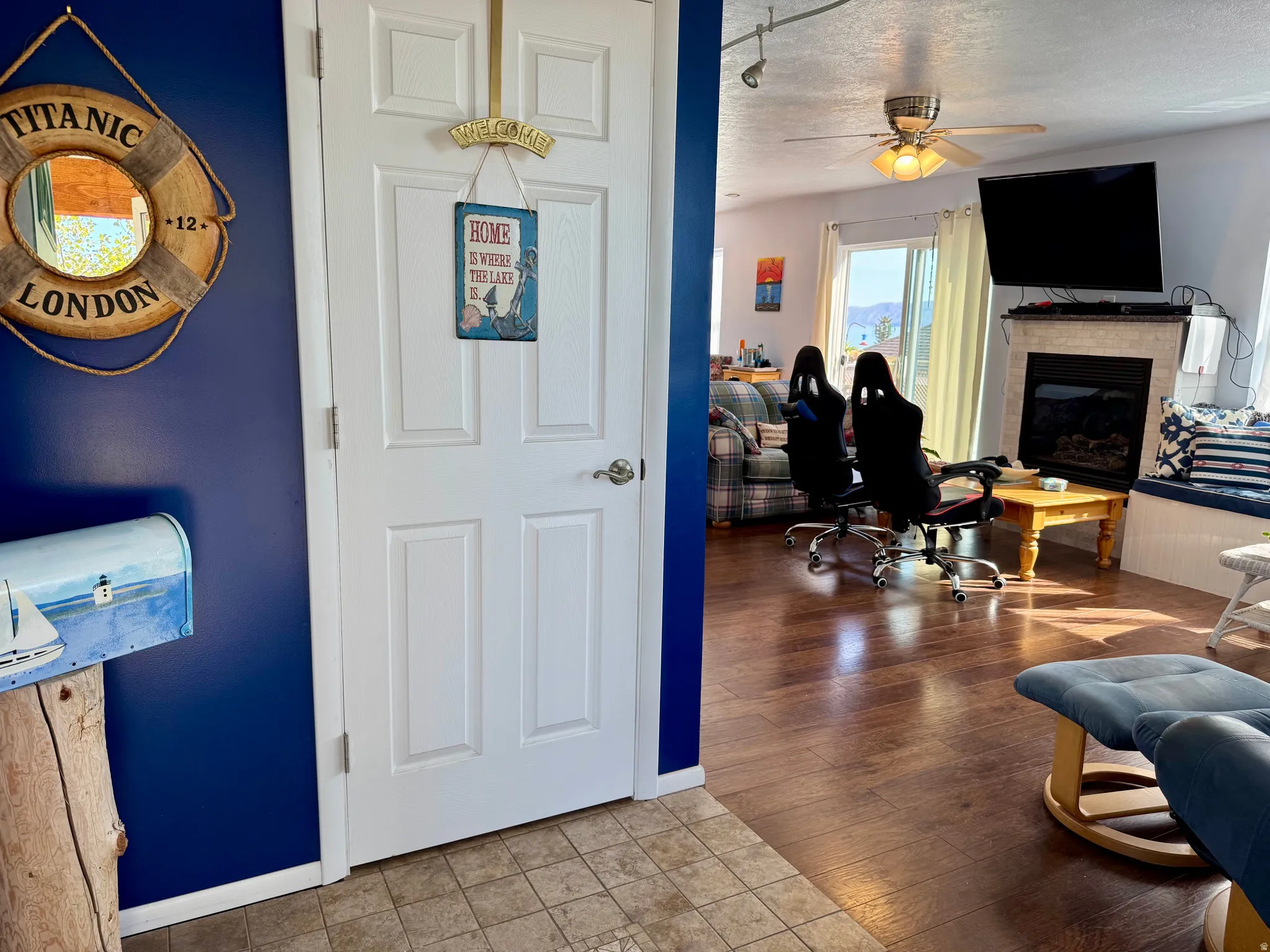 Wood-finish flooring throughout the living space, a built-in fireplace with a stone surround, and a ceiling fan