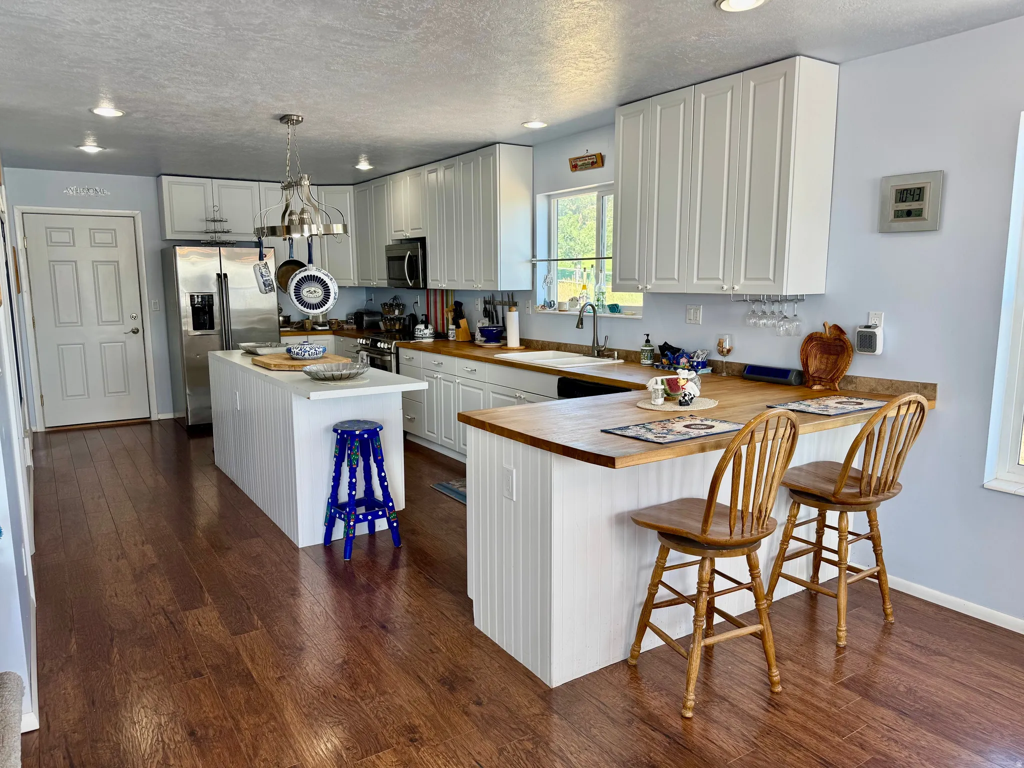 Kitchen featuring wood-finish flooring, white cabinetry, wood countertop, and stainless steel appliances