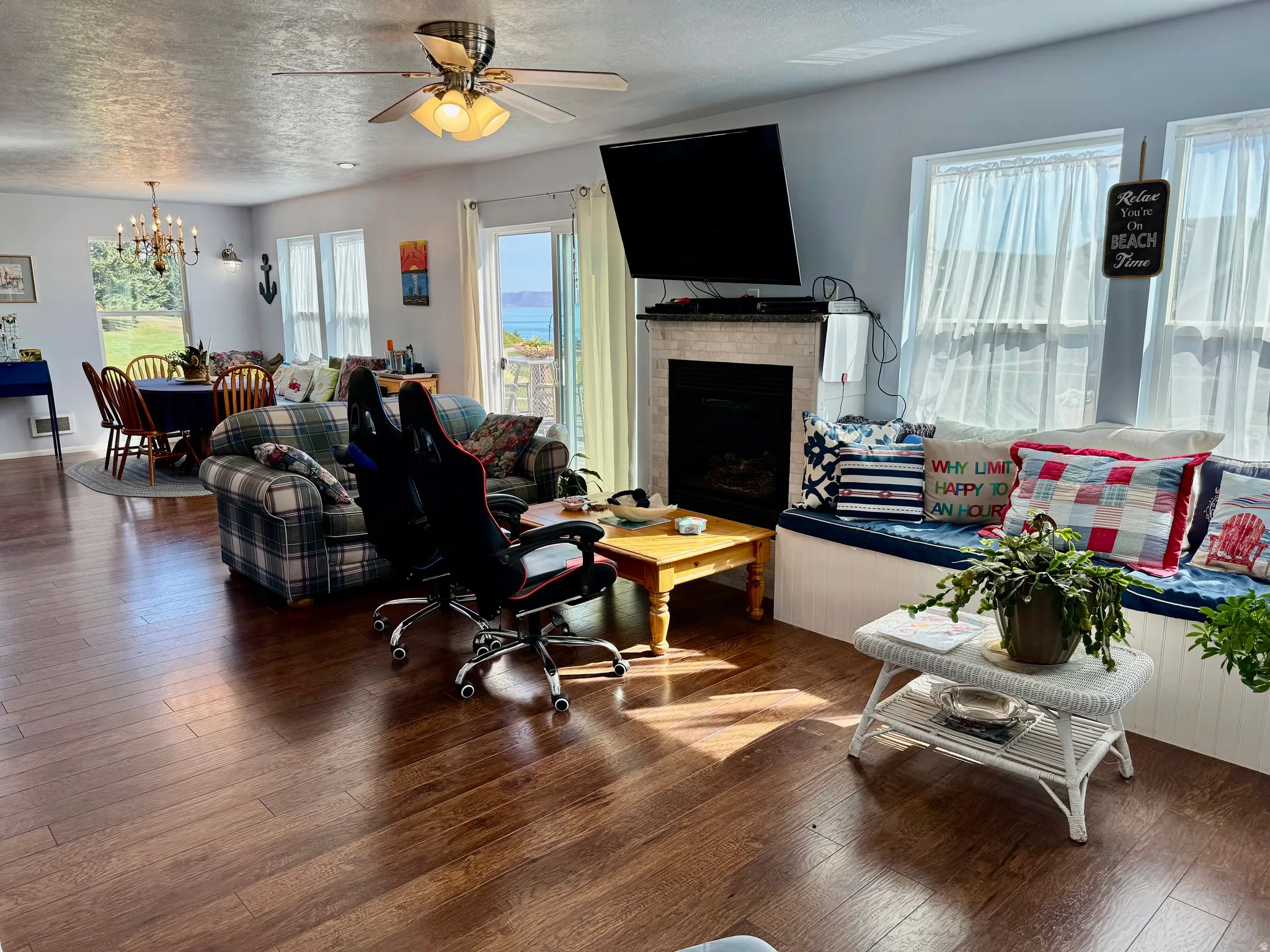 Wood-finish flooring throughout, with a built-in window bench, a fireplace with a stone surround, and an overhead ceiling fan with lighting