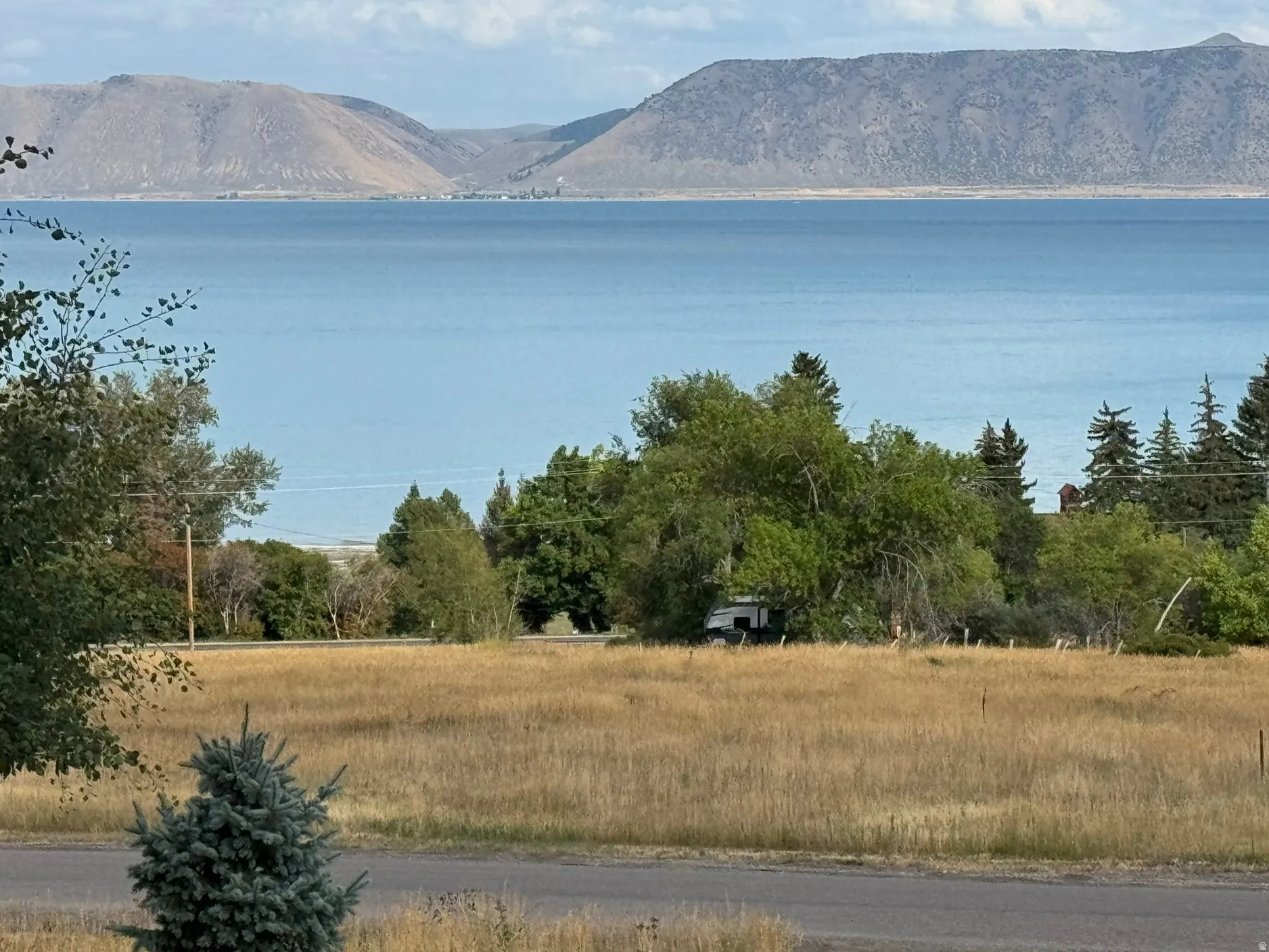 Expansive water feature with distant mountains, complemented by mature trees and natural vegetation