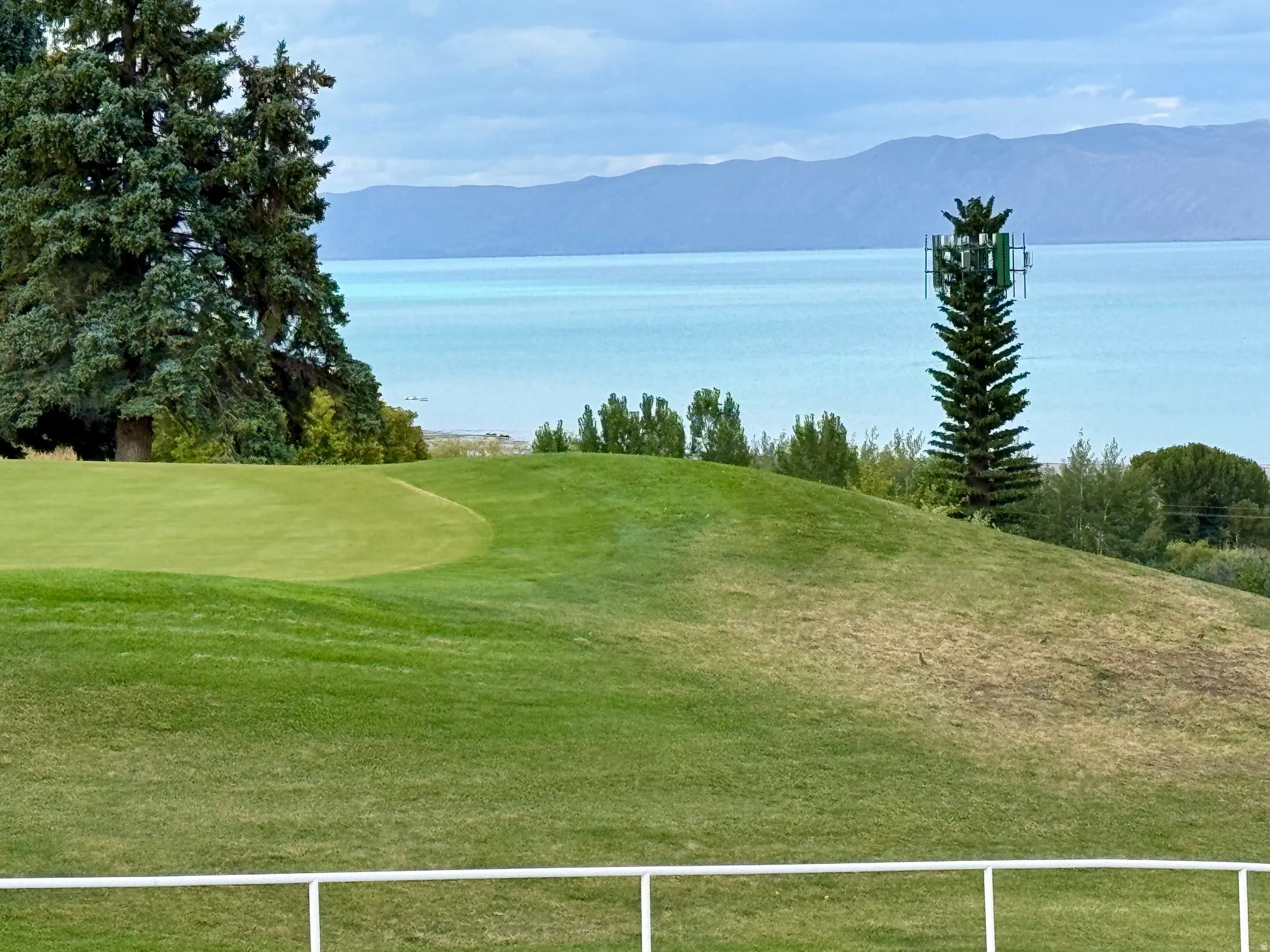 Manicured golf course green with expansive water and mountain scenery