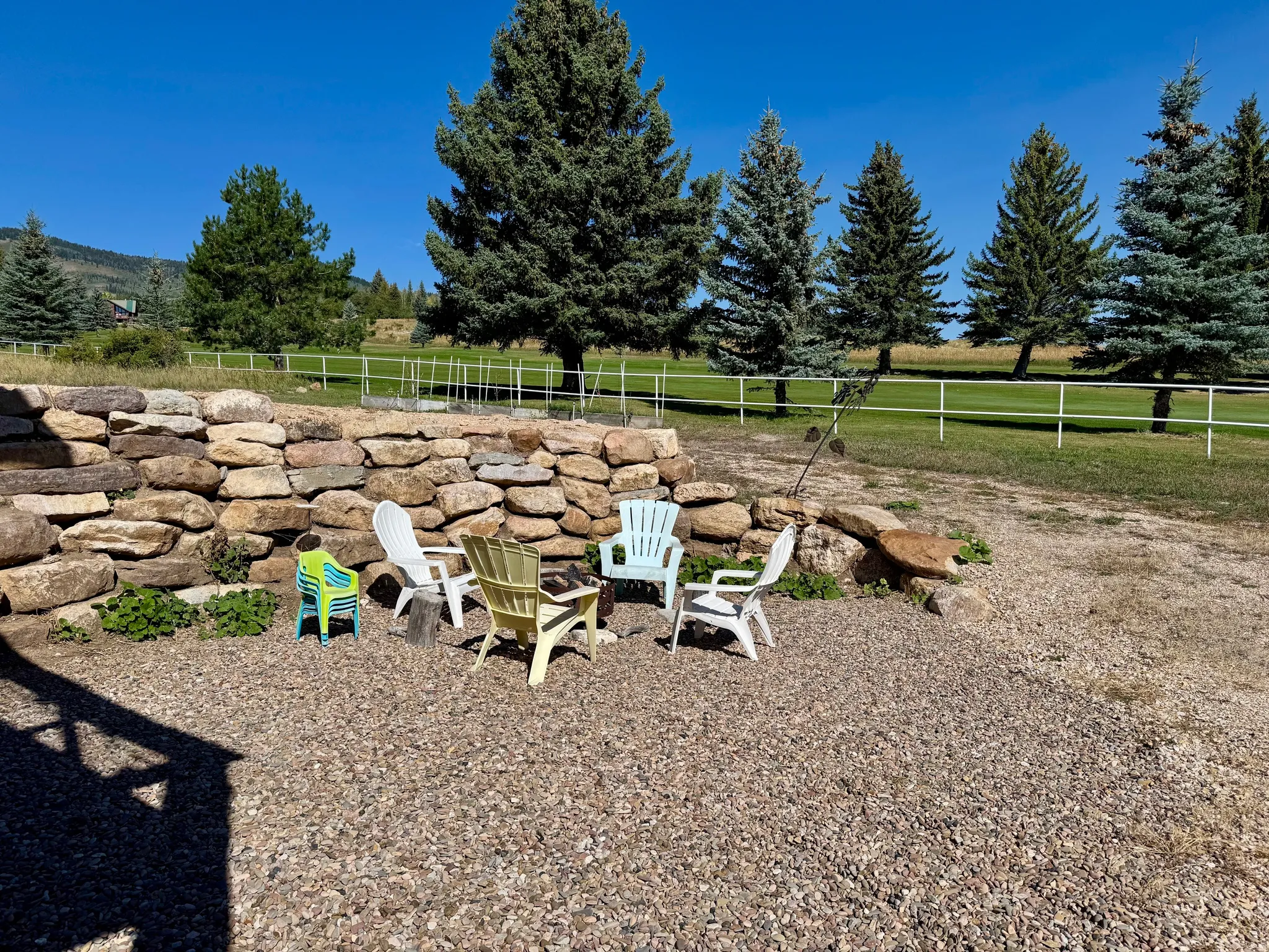 Firepit at gravel patio area with a stone retaining wall and #1 Fairway view