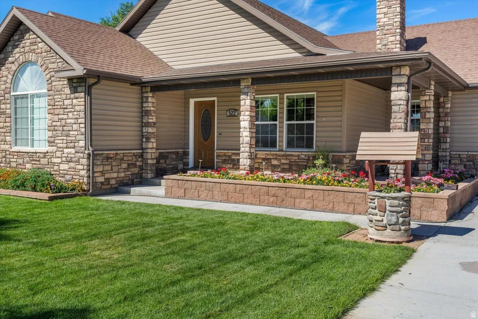 Stone veneer accents, arched window, covered front entry, brick paver retaining walls, and a stone-clad wishing well