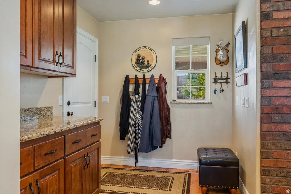 Built-in cabinetry with wood-finish doors and drawers, granite countertop, single-pane window, and brick-finish wall