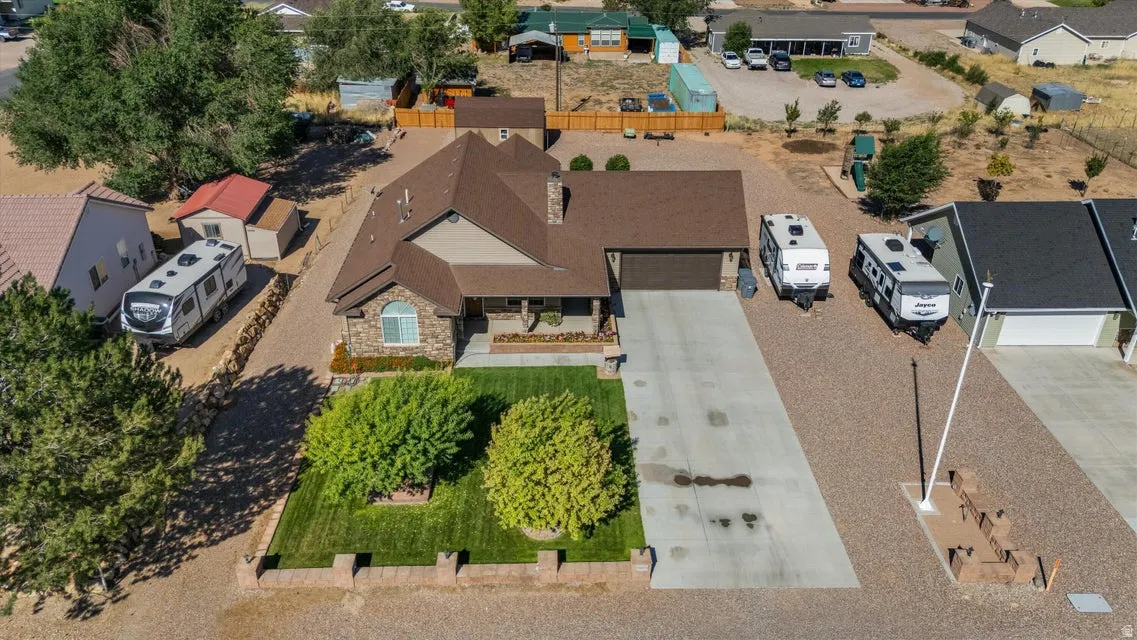 Stone façade with an attached garage, featuring a paved driveway and a landscaped front yard