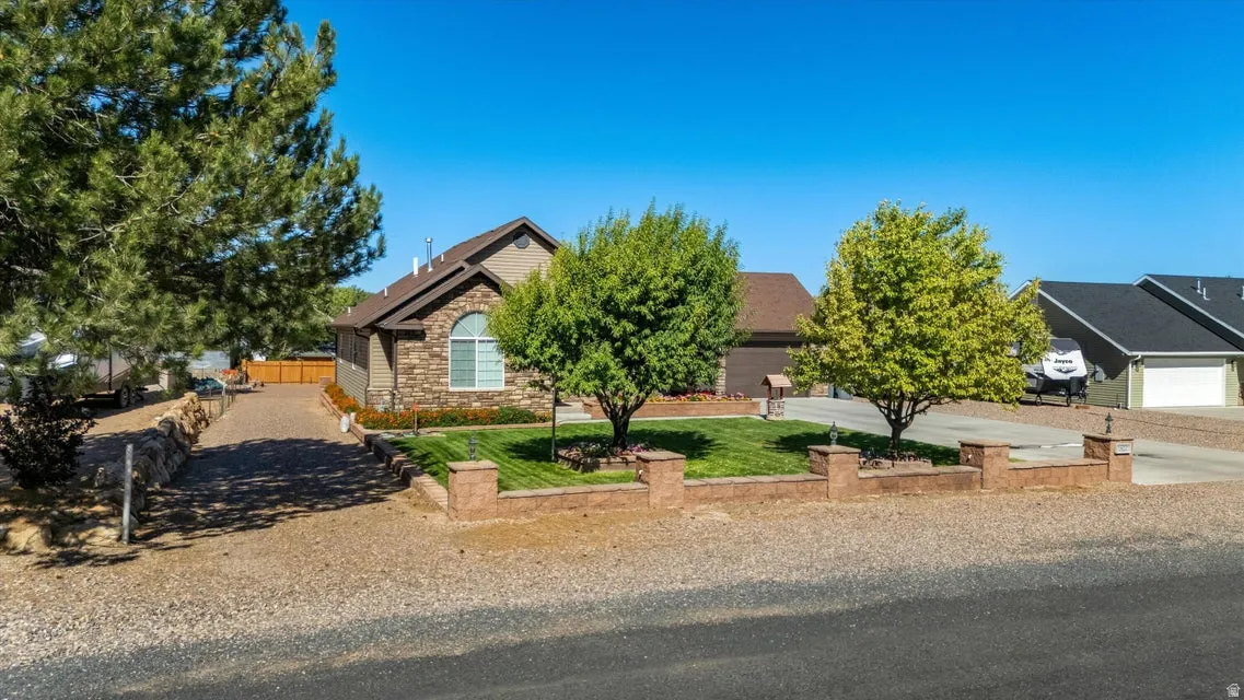 Stone veneer facade with an arched window, a well-maintained lawn, and a gravel driveway