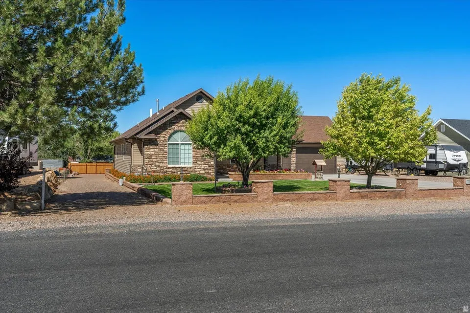 Stone and siding exterior with an arched window, attached garage, and a gravel driveway