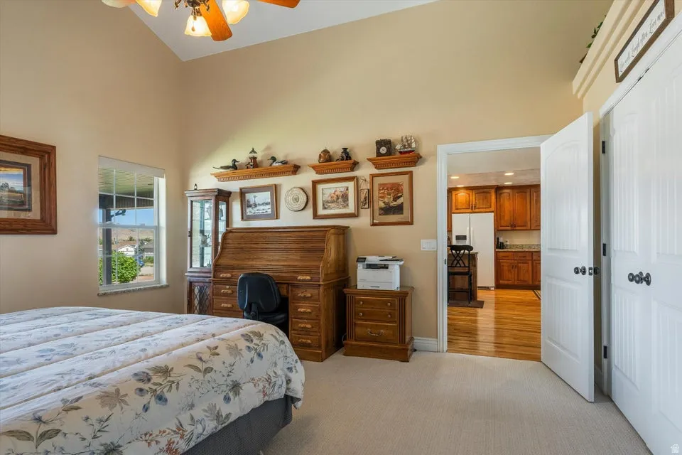 Vaulted ceiling with an attached ceiling fan, a window with a sill, and two white panel doors