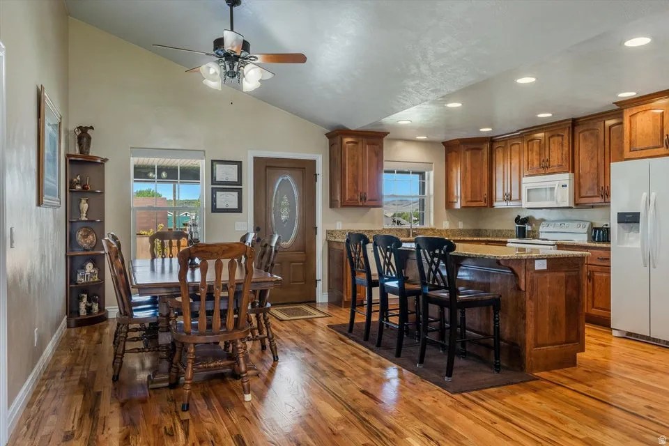Open concept living area featuring wood-finish flooring, vaulted ceiling, recessed lighting, and a ceiling fan