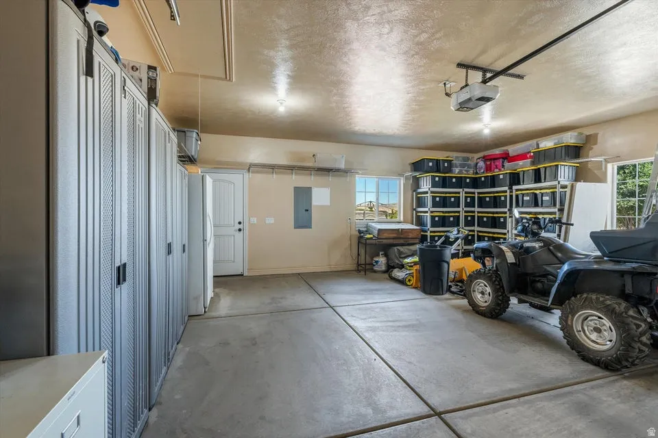 Concrete flooring, multiple windows, built-in storage cabinets, overhead lighting, and a garage door opener