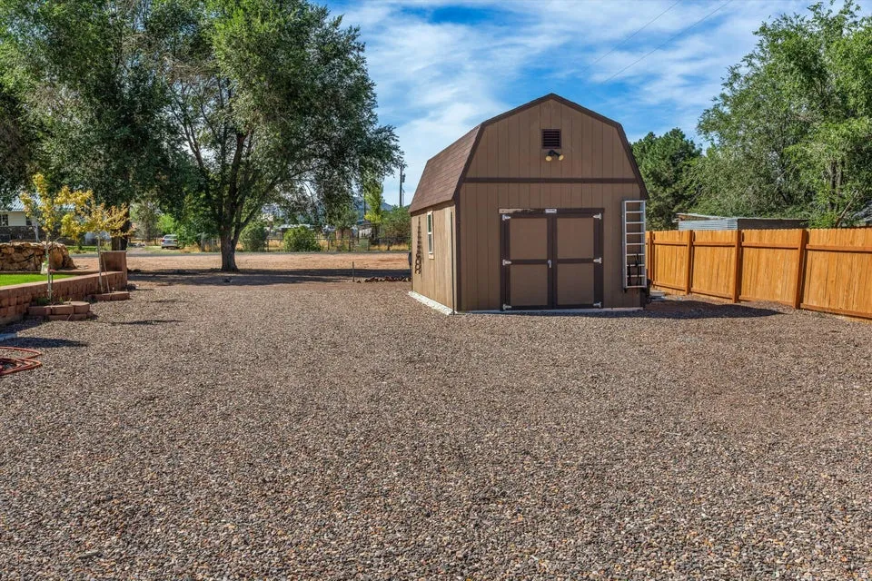 Gravel-covered yard featuring a wooden storage shed with a gambrel roof, double doors, and a side-mounted ladder