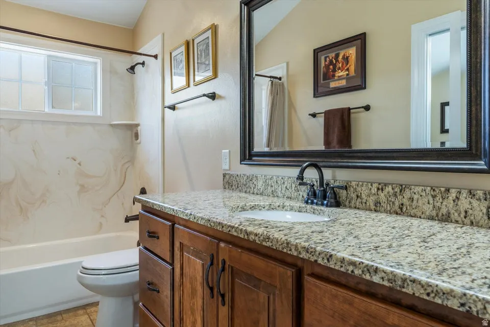 Granite countertop with integrated sink, wood-finish vanity cabinetry, and dark bronze fixtures