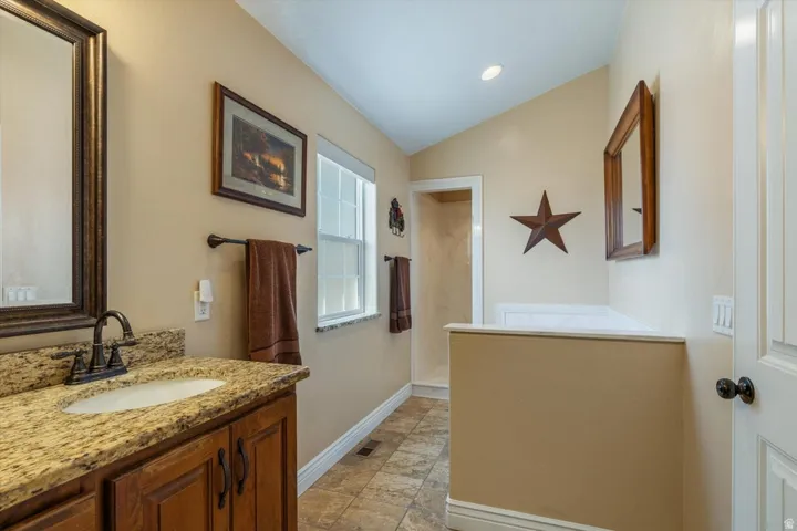 Vanity with a granite countertop, undermount sink, and dark bronze-finish faucet