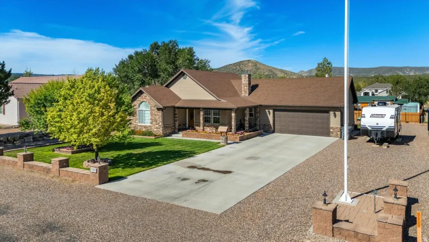 Stone veneer exterior with a covered front porch, attached two-car garage, and a concrete driveway
