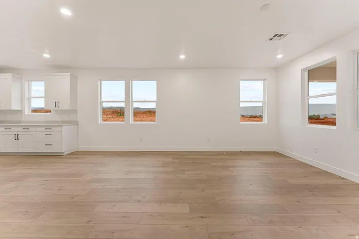 White cabinetry with dark hardware, light-toned wood-finish flooring, recessed lighting, and multiple windows