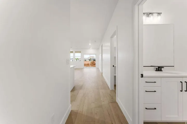 Light wood-finish flooring, white walls, and recessed lighting create a bright interior