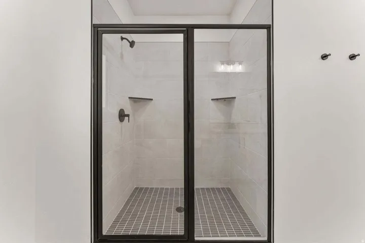Glass-enclosed shower with dark-toned framing and fixtures