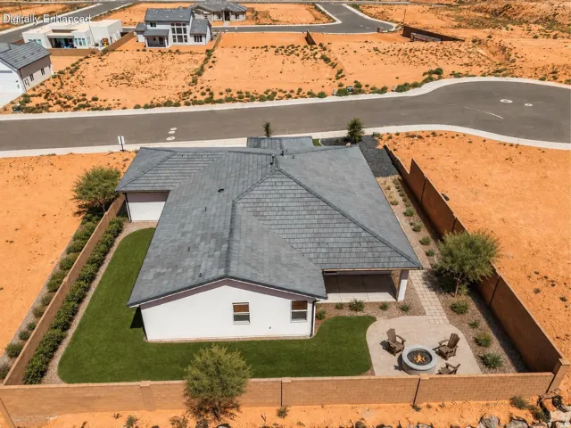 Paved patio with built-in fire pit, manicured lawn, and low-maintenance landscaping