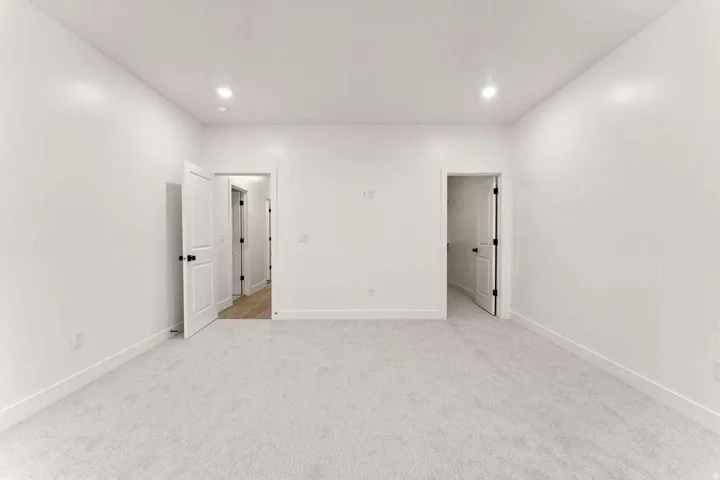 Plush carpeting, recessed lighting, white walls, and white trim