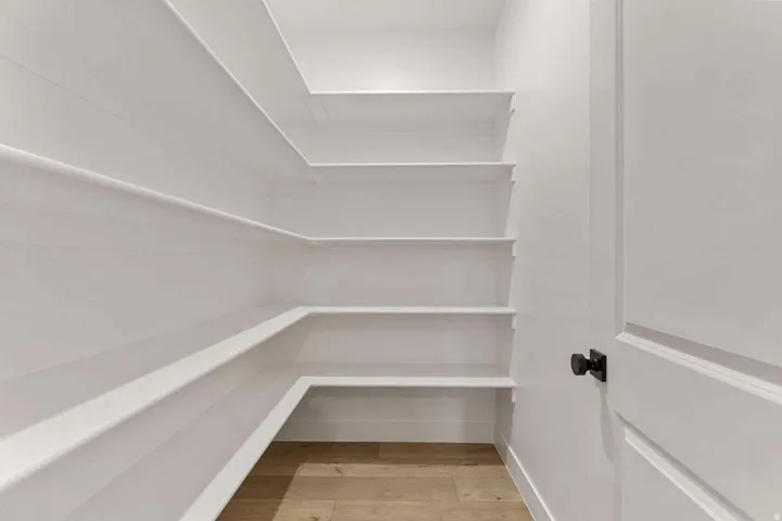 Built-in shelving, wood-finish flooring, white paneled walls, and a solid core door with a matte black knob