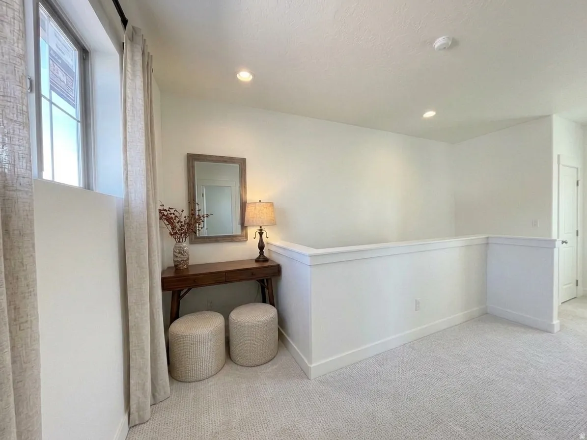Recessed lighting, light-toned carpeting, window with trim, white wall paneling, and a white door frame