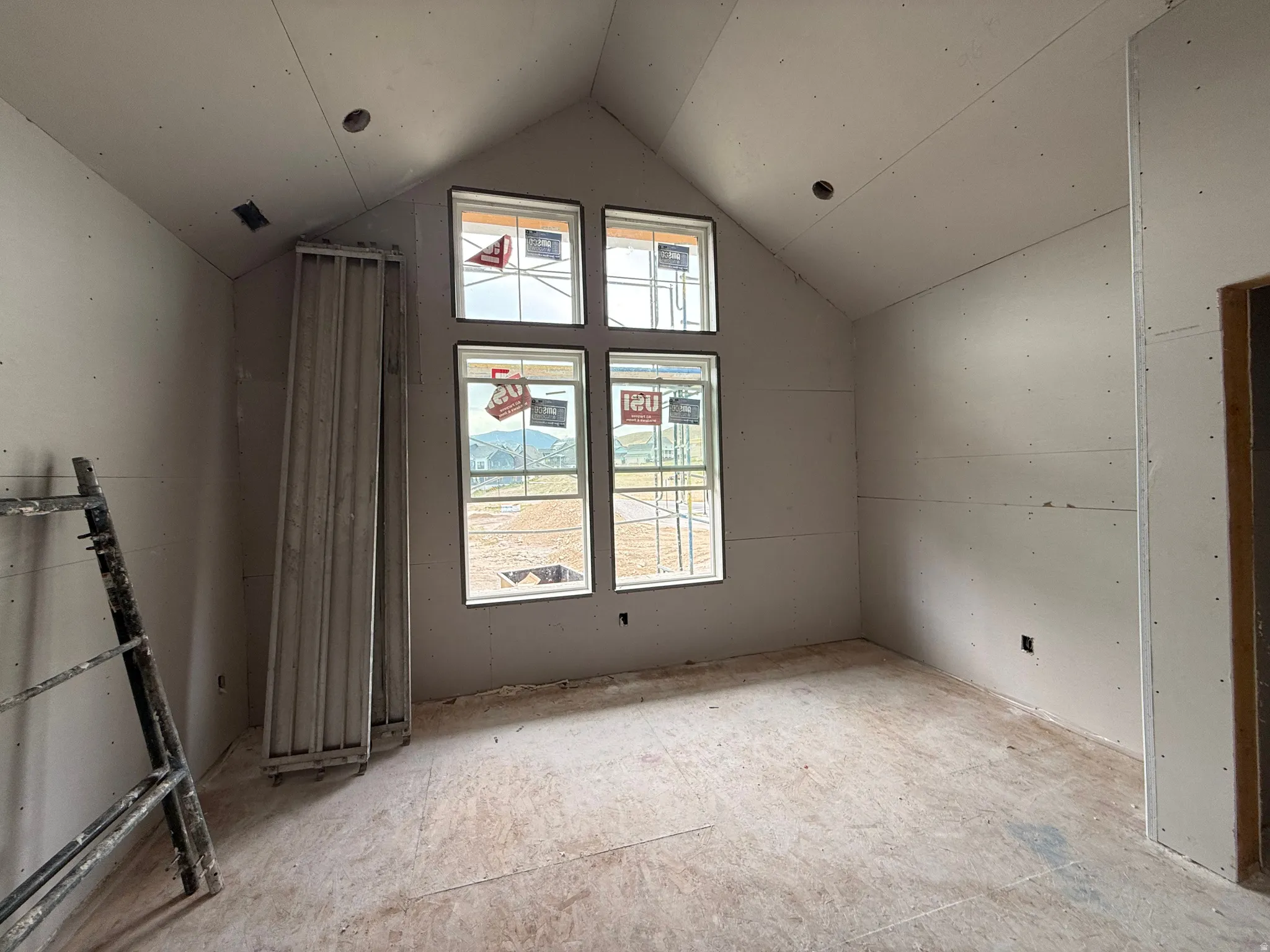 Vaulted ceiling, multiple windows, recessed ceiling light fixtures, unfinished drywall, unfinished subflooring