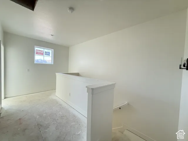 Upper-level landing with a window, white painted walls, and a staircase with a white handrail