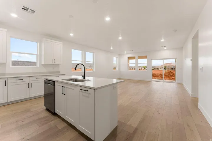 Open concept design featuring a central kitchen island with an integrated sink and black hardware