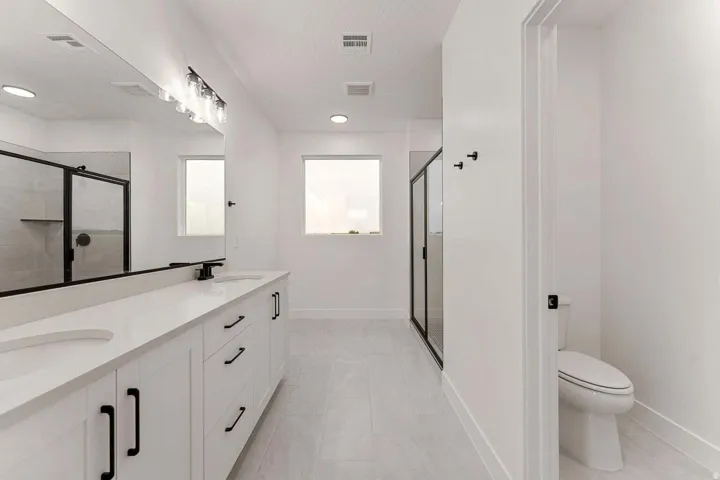 Dual vanity with undermount sinks, stone-finish countertop, and black fixtures