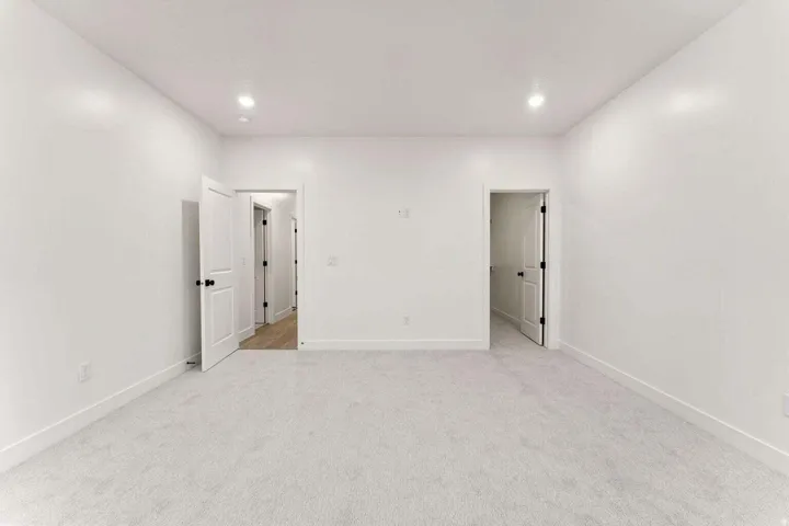 Recessed ceiling lighting, light gray carpeting, white walls, white trim, and white doors with matte black hardware