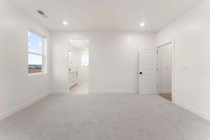 Recessed lighting, light gray carpeting, and white walls throughout