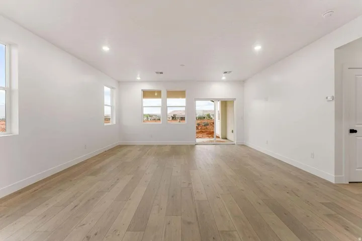 Expansive room featuring light wood-finish flooring, recessed lighting, multiple windows, and a sliding glass door
