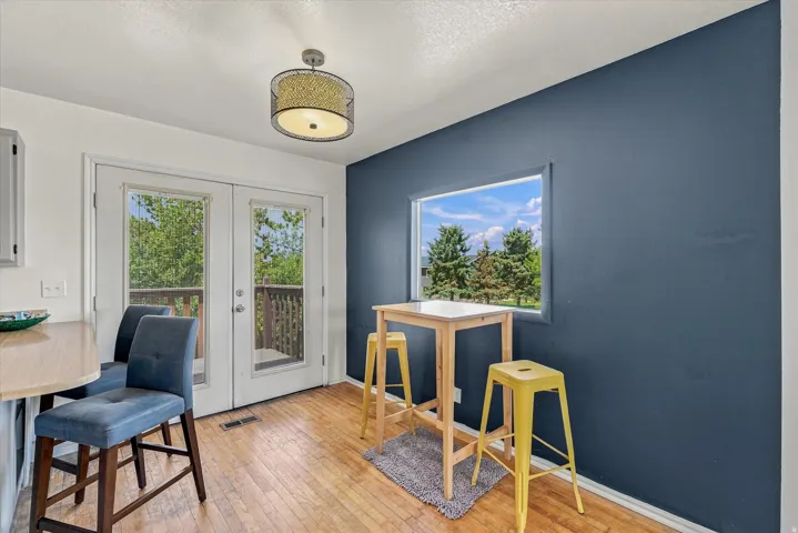 Hardwood-finish flooring, built-in breakfast bar, French doors, large window, and overhead drum pendant light fixture