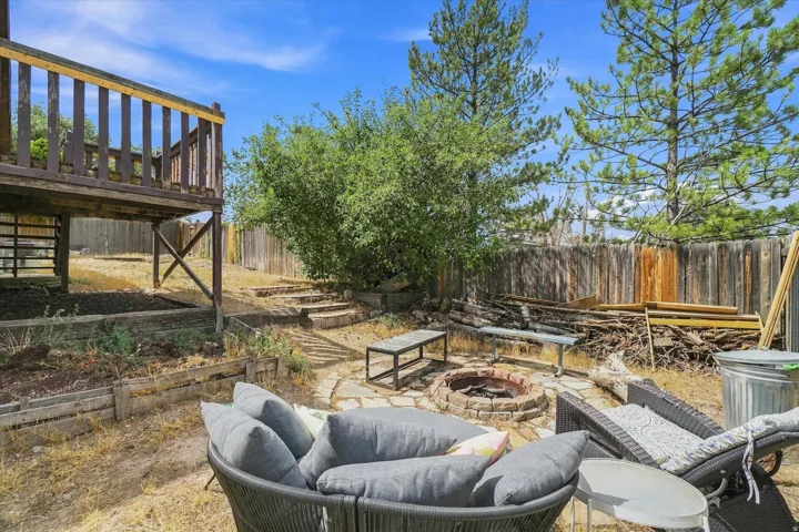 Tiered backyard featuring a wood deck, stone fire pit, and wood fencing