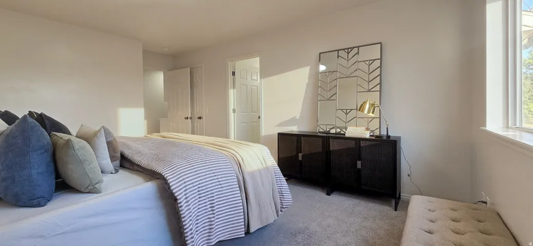White walls with a window, gray carpeting, and white doors