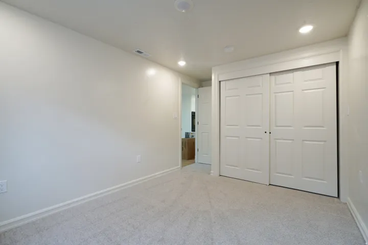 Neutral tone walls, recessed lighting, light-colored carpeting, white trim, and white sliding closet doors