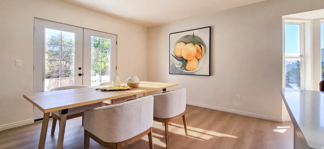 Light wood-finish flooring, white double French doors, large bay window, and a white countertop