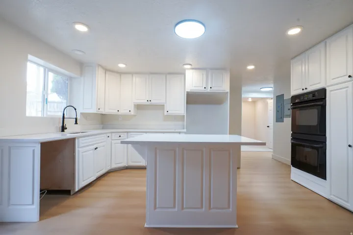 Kitchen featuring white cabinetry, light-toned wood-finish flooring, recessed lighting, and a double wall oven