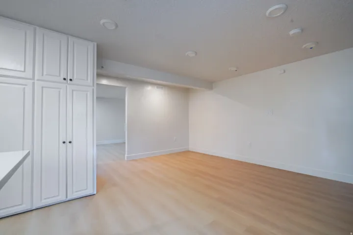 White shaker-style cabinetry with dark hardware, recessed ceiling lighting, wood-finish flooring, and white baseboards