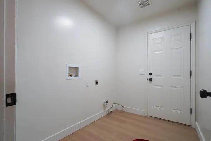 Dedicated utility area featuring wood-finish flooring and a paneled door
