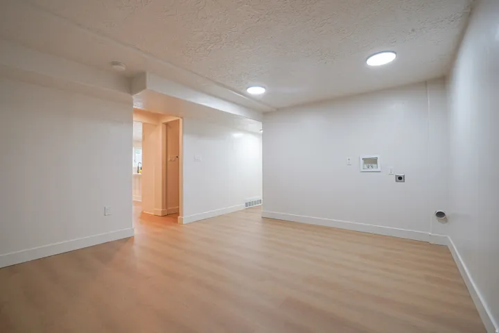 Recessed ceiling lighting, wood-finish flooring, and white baseboards
