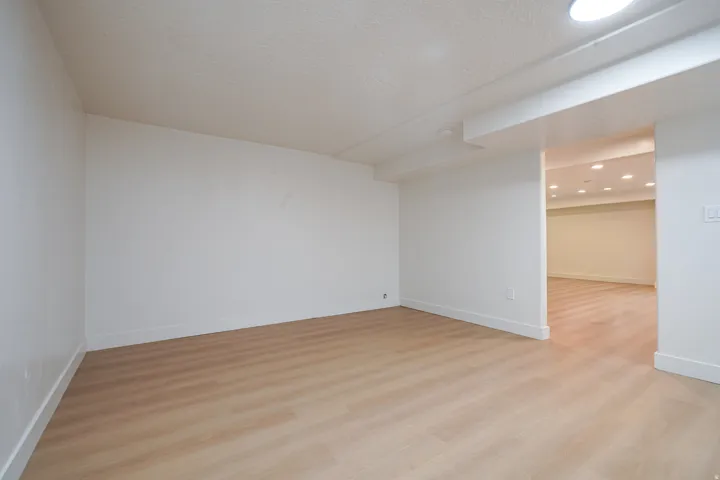 Expansive room with wood-finish flooring, recessed lighting, and crisp white walls