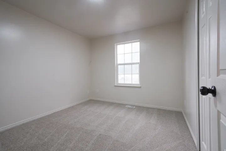 Light gray wall-to-wall carpeting, white painted walls, and a single window with white trim