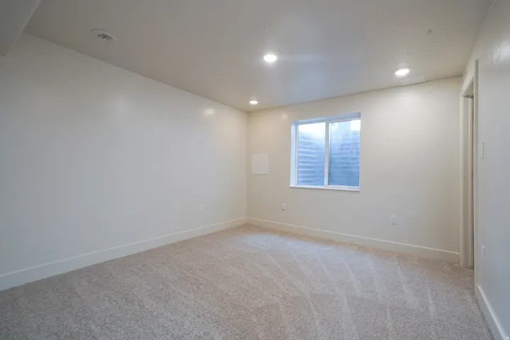 Recessed lighting, light gray carpet, white walls, and a white-framed window